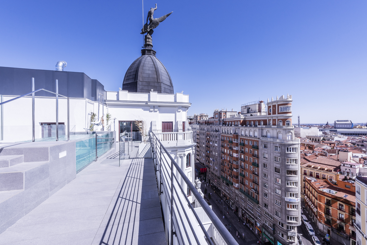 Azotea de edificio emblematico de Gran vía en Madrid con vistas a la ciudad y piscina de cristal.
