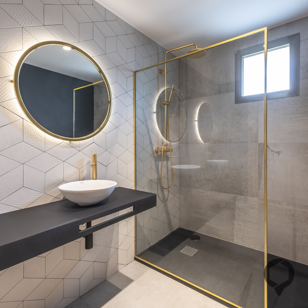 Vista de baño detalles dorados en grifería, espejos y mampara de ducha.